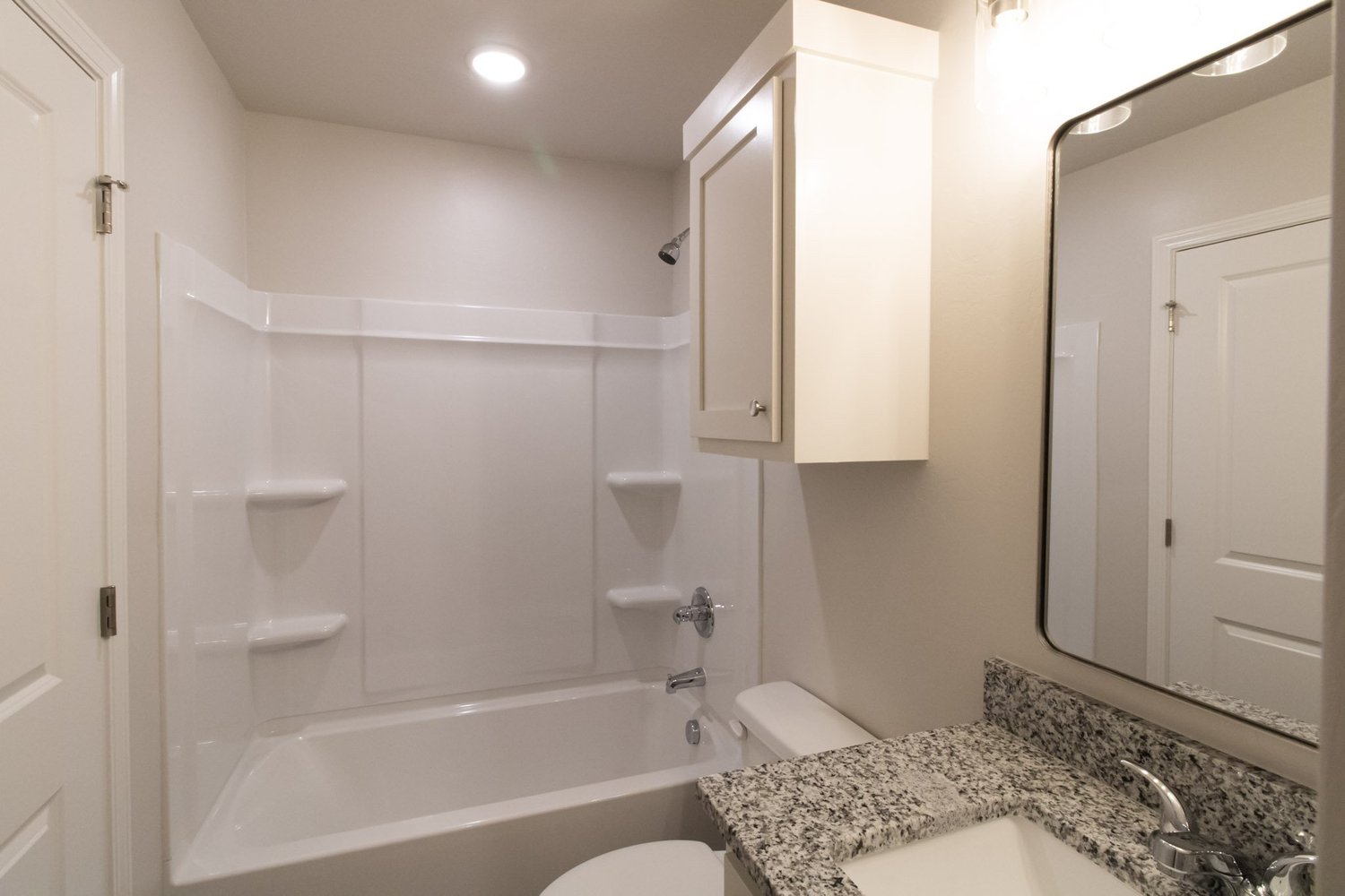 Bathroom with tub and shower, granite vanity, and framed mirror