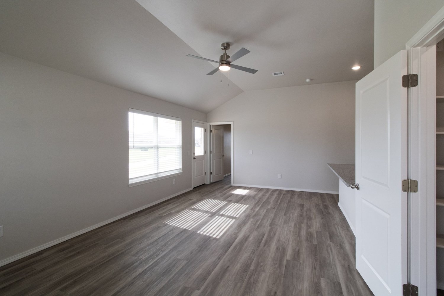 Living room with ceiling fan and sunlight on new wood-look floors