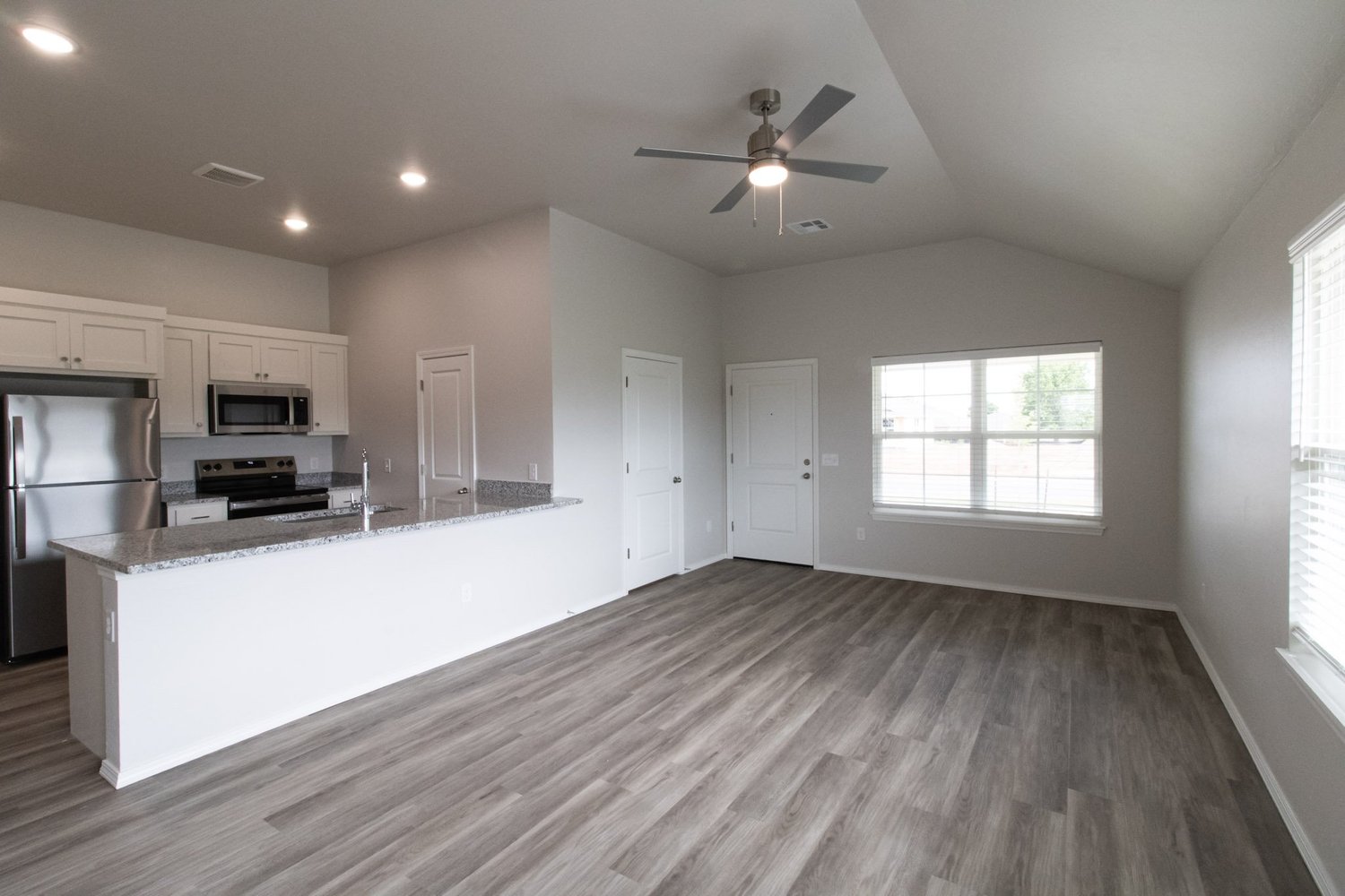 Open-concept kitchen with granite island, stainless appliances, and wood-look flooring